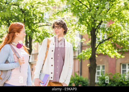 Young male and female college students talking while walking on street Stock Photo