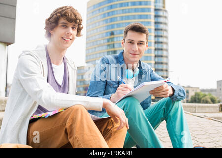 Portrait of young male college students studying on steps against building Stock Photo