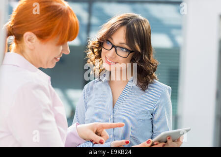 Smiling businesswomen discussing over tablet PC in office Stock Photo