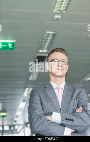Middle-aged businessman standing with arms crossed in office Stock Photo