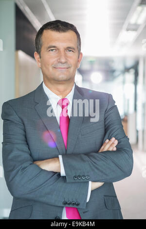 Portrait of middle-aged businessman standing with arms crossed in office Stock Photo