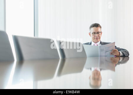 Middle-aged businessman reading book at conference table Stock Photo