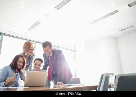 Businesspeople using laptop at conference table Stock Photo