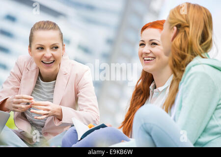 Happy young female college friends studying outdoors Stock Photo