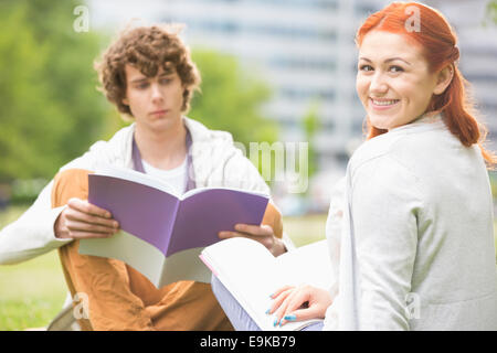 Portrait of happy young woman with male friend studying at college campus Stock Photo