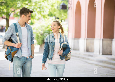 Young college friends talking while walking at campus Stock Photo