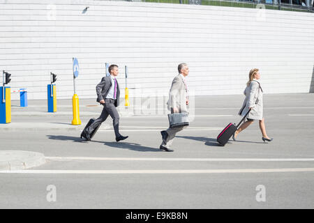 Side view of businesspeople with luggage walking on street Stock Photo