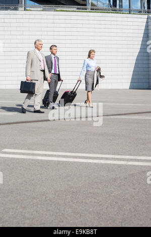 Businesspeople with luggage walking on street Stock Photo