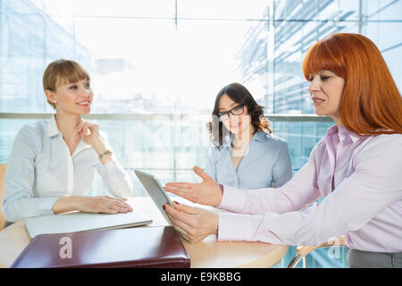 Businesswomen discussing over table PC at table in office Stock Photo