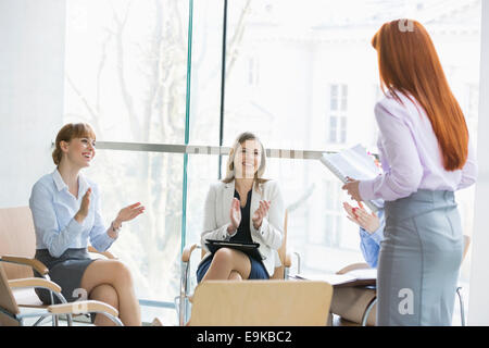 Happy businesswomen clapping for colleague after presentation in office Stock Photo