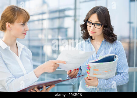Businesswoman showing document to female colleague in office Stock Photo