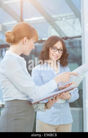 Businesswoman showing document to colleague in office Stock Photo