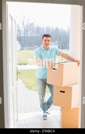 Full-length portrait of man with stacked cardboard boxes at new house Stock Photo