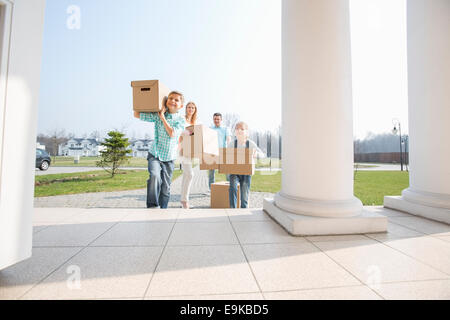 Family with cardboard boxes entering into new house Stock Photo