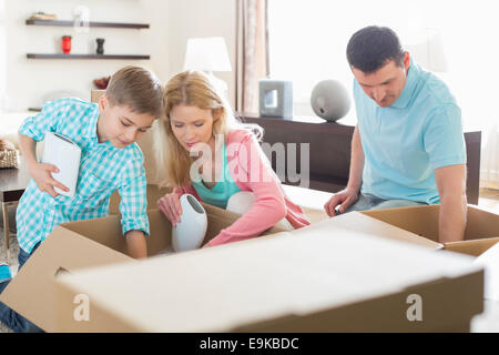 Family unpacking cardboard boxes in new house Stock Photo