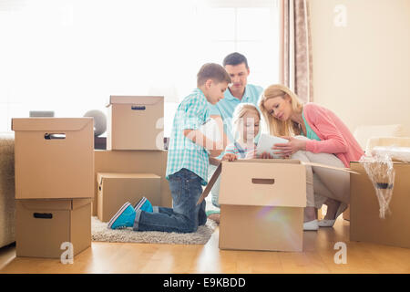 Family unpacking cardboard boxes at new home Stock Photo