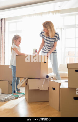 Mother and daughter packing cardboard boxes at home Stock Photo