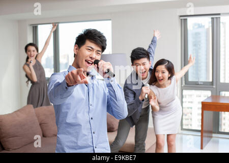 Happy young friends singing and dancing in living room Stock Photo
