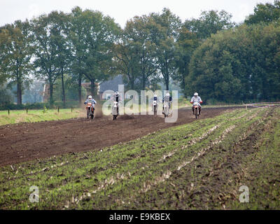 Group of cross motorcyclists speeding through a farm field in Ruurlo, the Netherlands, during an enduro event. Stock Photo