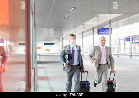 Middle aged businessmen with luggage rushing on railroad platform Stock Photo