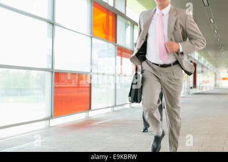 Midsection of businessmen rushing on railroad platform Stock Photo