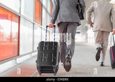 Rear view of businessmen with luggage running on railroad platform Stock Photo