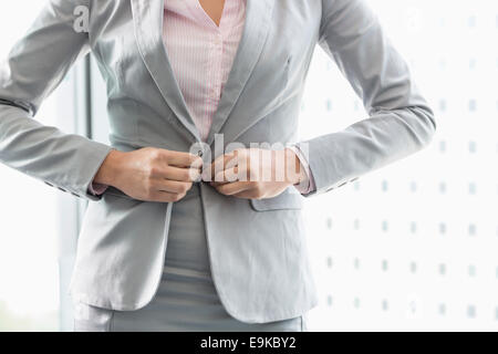 Midsection of businesswoman buttoning her blazer Stock Photo