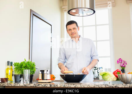 Portrait of confident man preparing food in kitchen Stock Photo