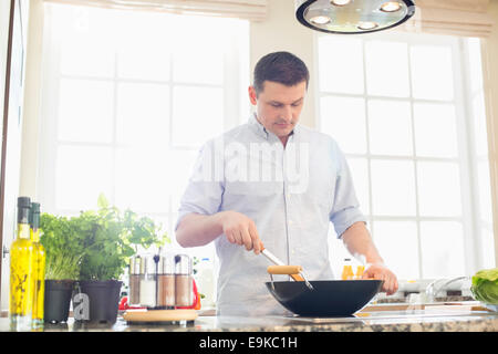 Middle-aged man preparing food in kitchen Stock Photo