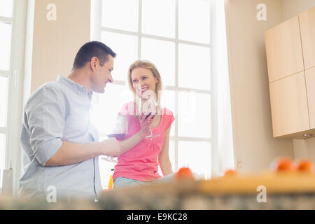 Happy couple drinking red wine in kitchen Stock Photo