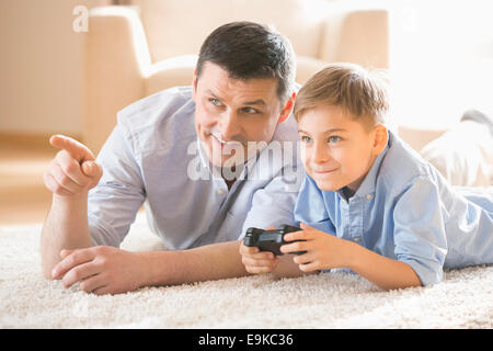 Father and son playing video game on floor at home Stock Photo