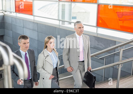 Businesspeople walking up stairs in train station Stock Photo