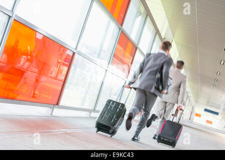 Rear view of middle aged businessmen with luggage rushing on railroad platform Stock Photo