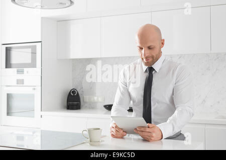 Mid adult businessman using tablet PC in kitchen