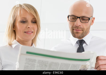 Mid adult business couple reading newspaper in kitchen Stock Photo