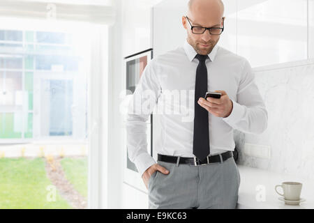 Mid adult businessman text messaging through smart phone at home Stock Photo