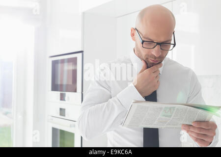 Mid adult businessman reading newspaper at home Stock Photo