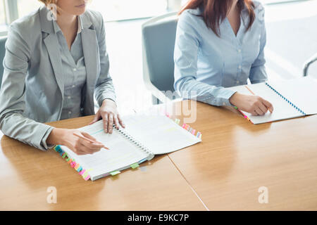 Midsection of businesswomen with books at table in office Stock Photo