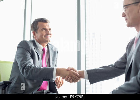 Mature businessmen shaking hands in office Stock Photo