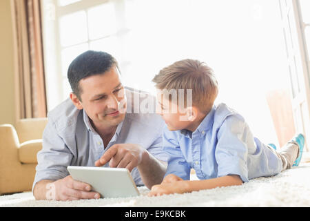 Father and son using digital table on floor at home Stock Photo