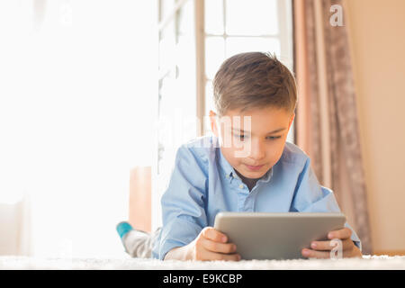 Boy using digital tablet while lying on floor at home Stock Photo