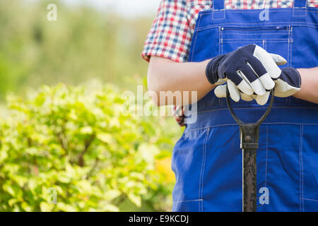 Midsection of gardener holding spade in plant nursery Stock Photo