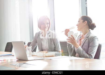Young businesswomen having lunch at table in office Stock Photo