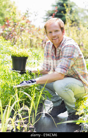 Full-length portrait of happy man holding potted plant at garden Stock Photo