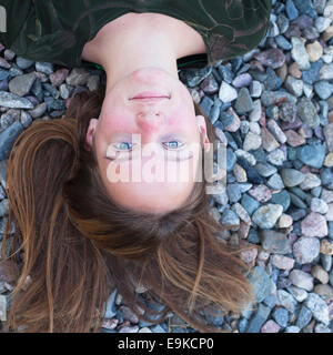 Beautiful young girl close-up lying on the sea pebbles. Stock Photo