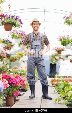 Full-length portrait of happy gardener standing at greenhouse Stock Photo
