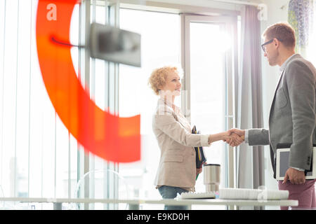 Creative business colleagues shaking hands in office Stock Photo