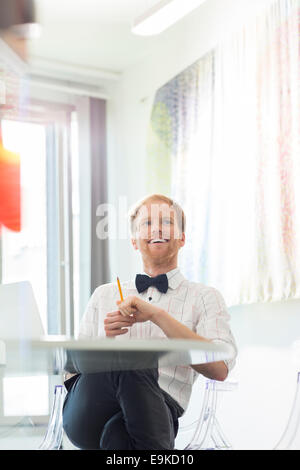 Happy businessman looking away in creative office Stock Photo
