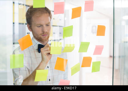 Creative businessman writing on sticky paper at office Stock Photo