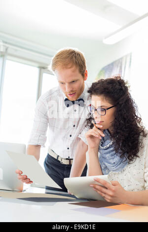 Businesspeople discussing over samples at desk in creative office Stock Photo